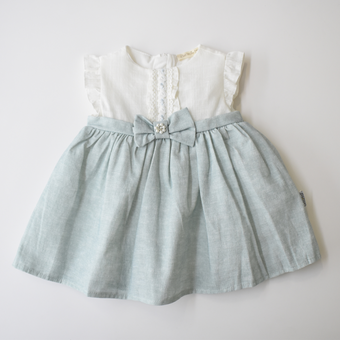 Baby girl dress with white ruffle-sleeve bodice, lace front detail, and light blue skirt accented by a bow with pearl embellishment at the waist.