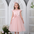 Jeune fille portant une robe rose clair avec une jupe en tulle et un gros détail de fleur, assortie à un bandeau rose