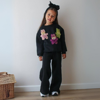 Young girl in a white off-shoulder communion dress with floral lace bodice and flowing tulle cape sleeves, styled for formal occasions.