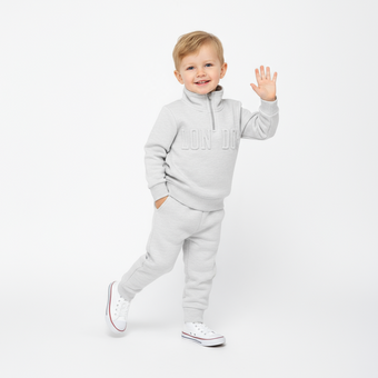 Child wearing a gray tracksuit on a white background