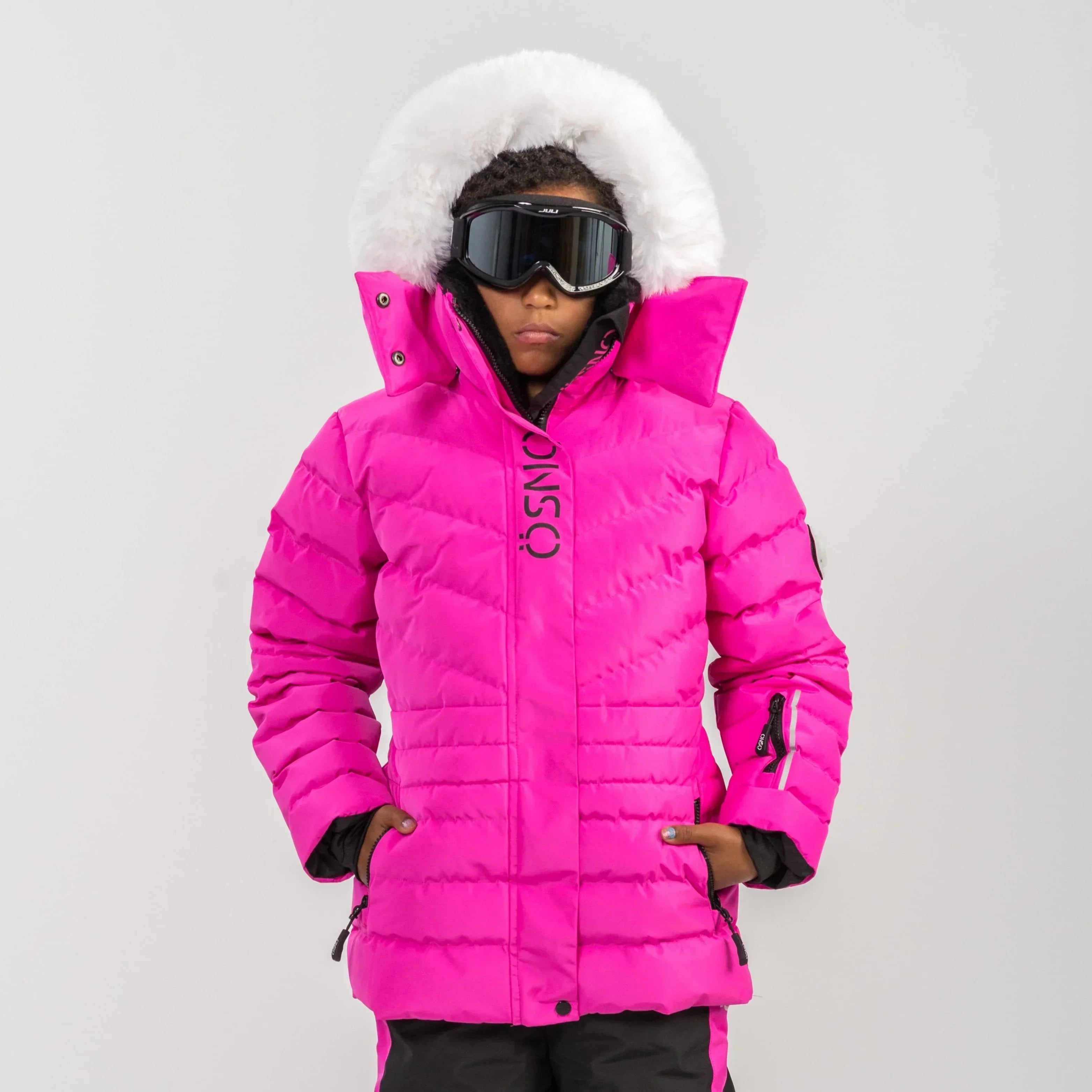 ÖSNO pink kids' ski jacket with white fur-trim hood, front view on model wearing ski goggles.