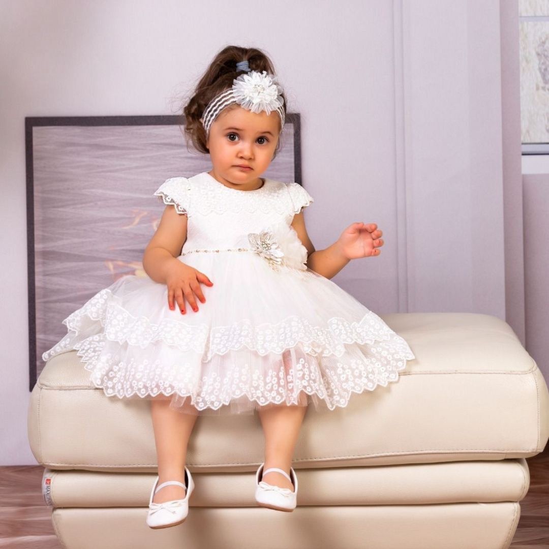 Fillette portant une robe blanche en dentelle avec bandeau fleur et ballerines assorties