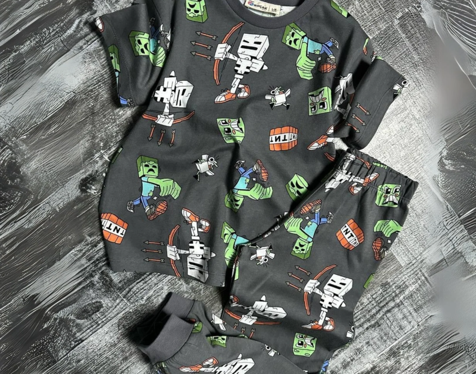 Grey monster-print pyjama top and pants folded flat.