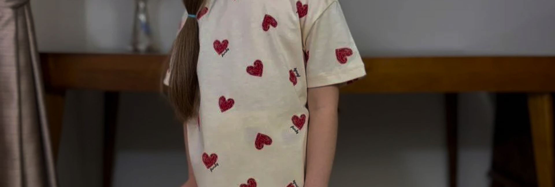 A girl in cream pyjamas with a red heart print.