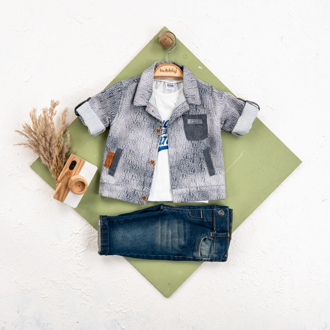 Toddler outfit with printed gray jacket, white graphic tee, and dark blue jeans laid flat with a wooden toy camera.